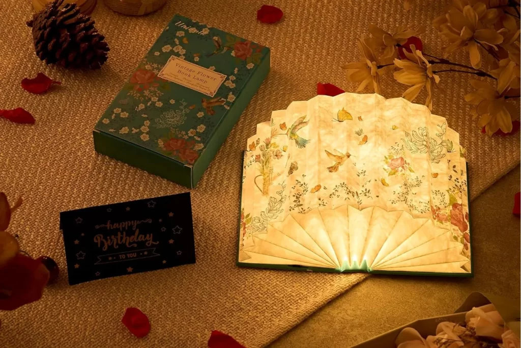 Foldable book lamp that opens like a book and emits soft warm light, displayed on a cozy reading table.